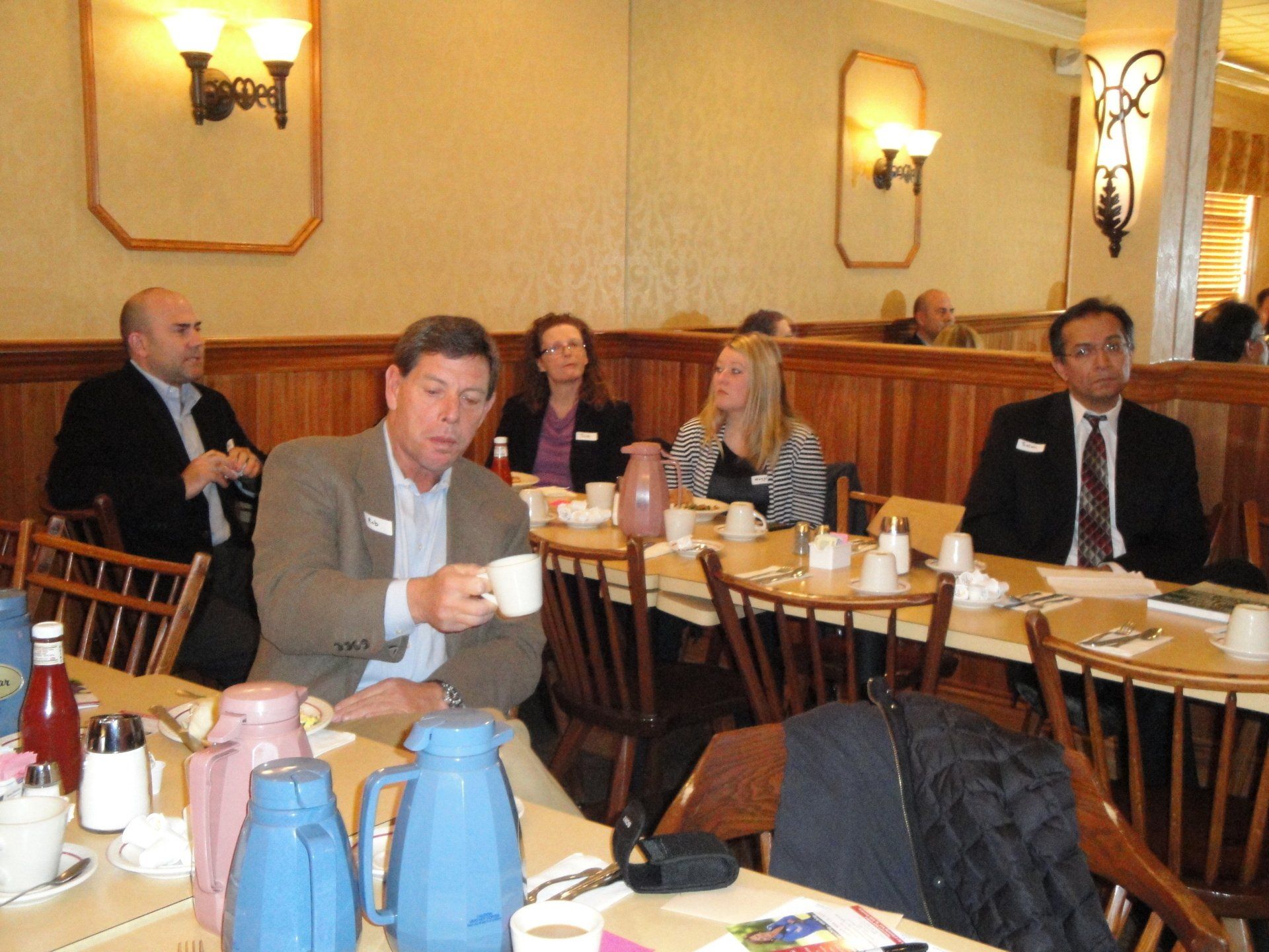 A group of people are sitting at tables drinking coffee