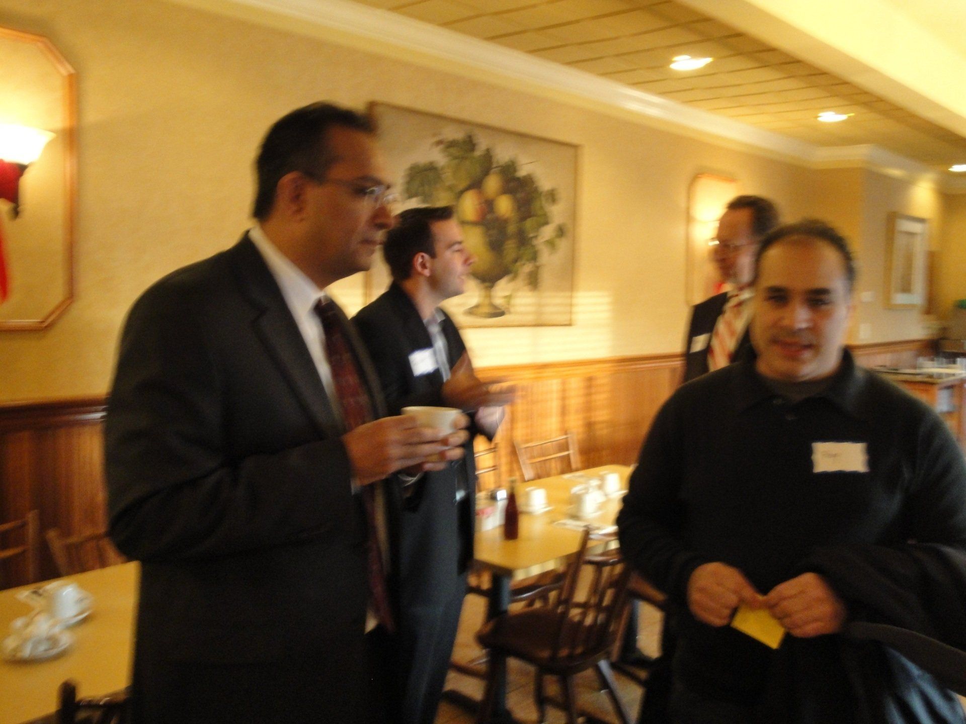 A group of men are standing around a table drinking coffee