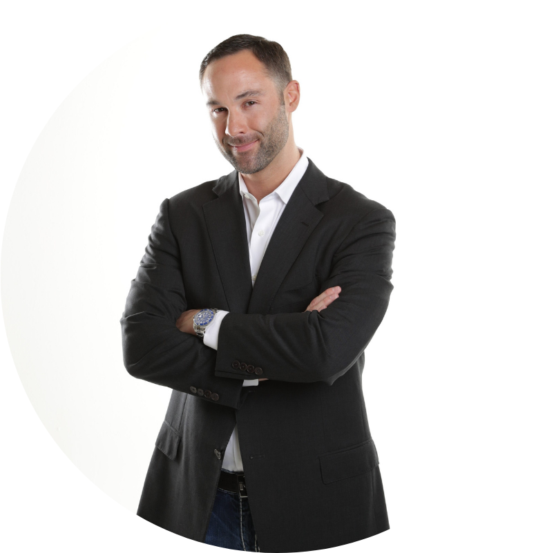 Man in a black suit, arms crossed, smiling at the camera against a white background.