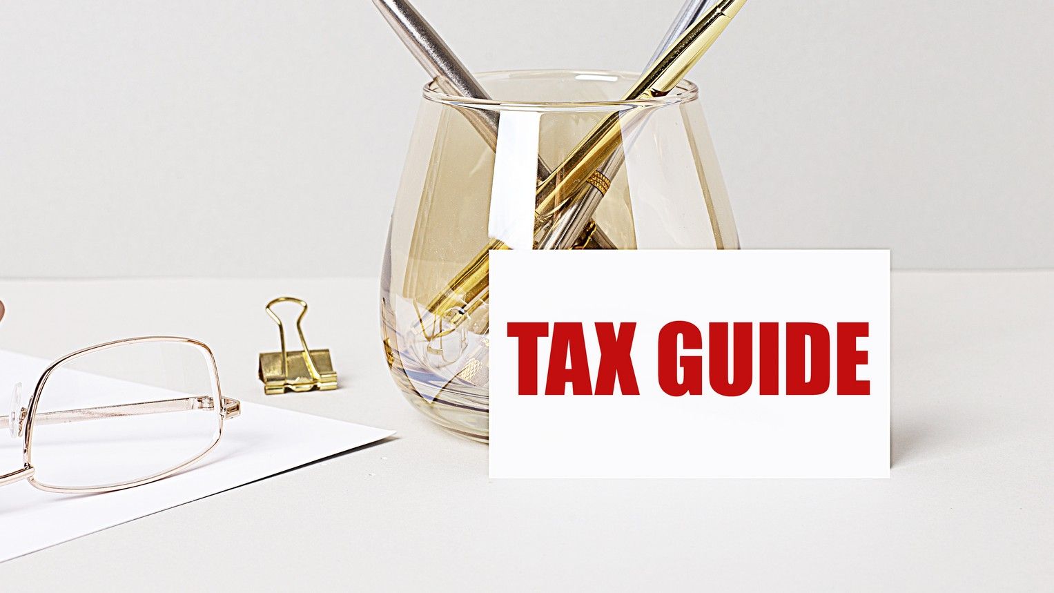 A glass filled with pens and a sign that says tax guide.