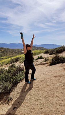 A woman in a blue bra and shorts is standing in front of a white wall.