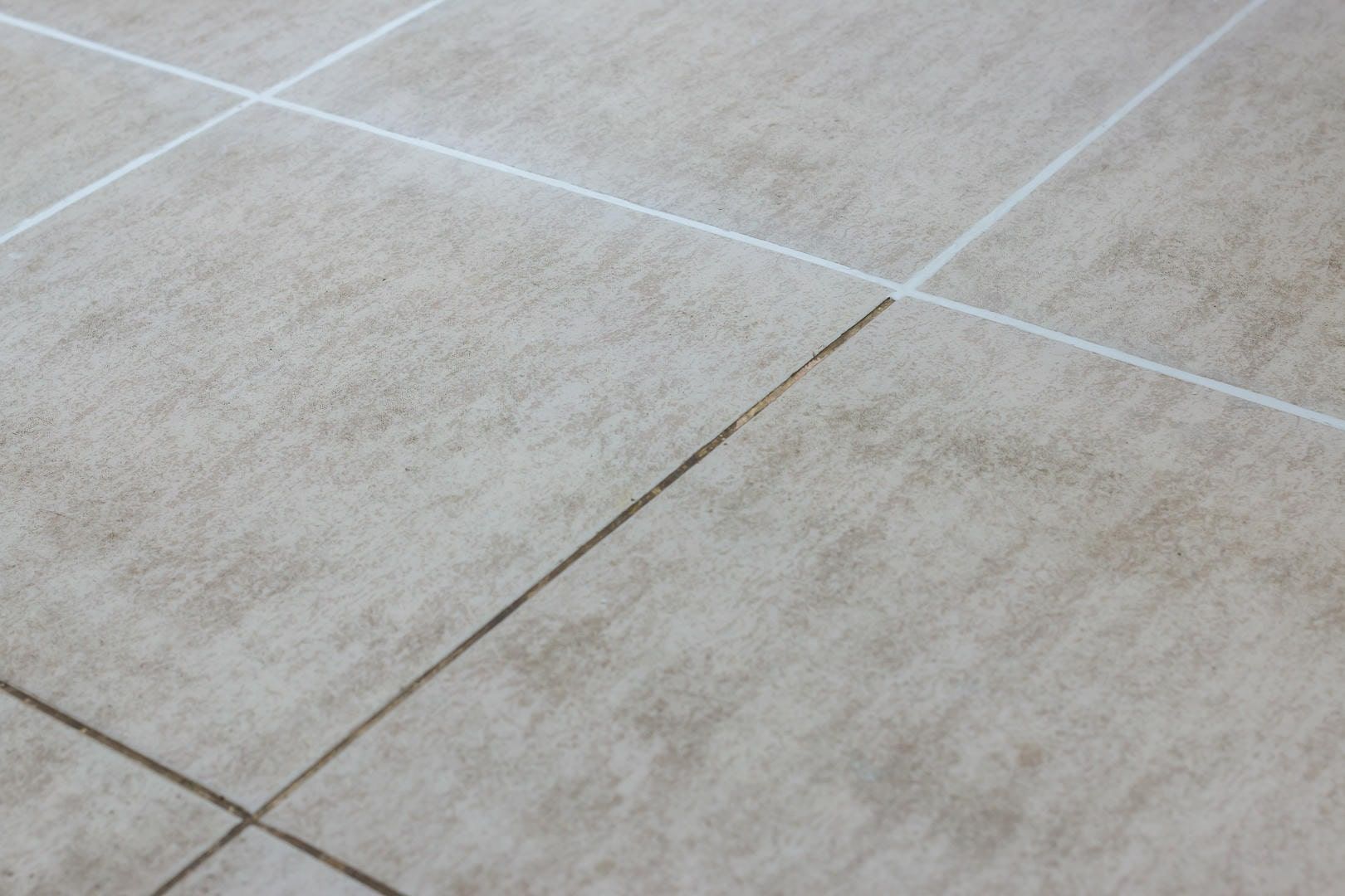 Close-up of beige tile flooring with white grout lines.