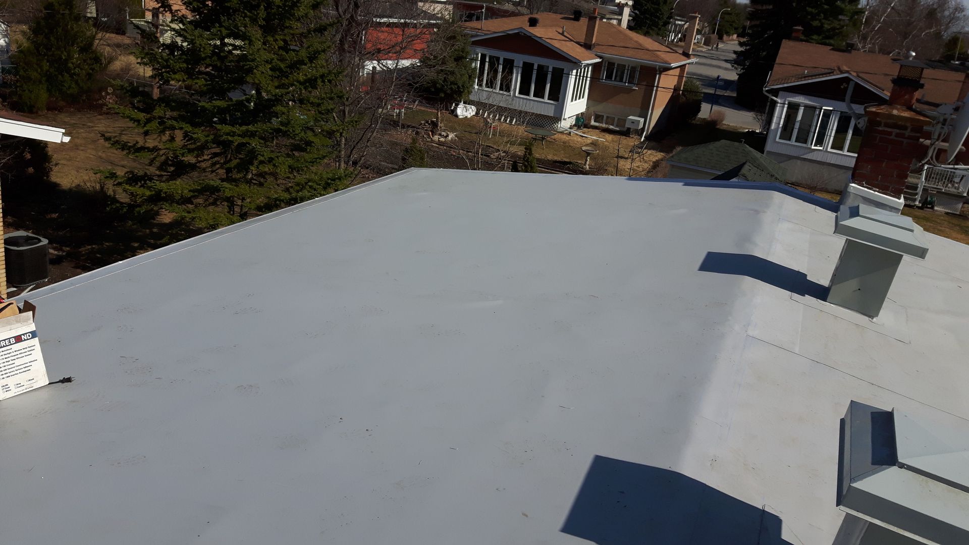 Une vue aérienne d'un toit avec des cheminées et des maisons en arrière-plan.