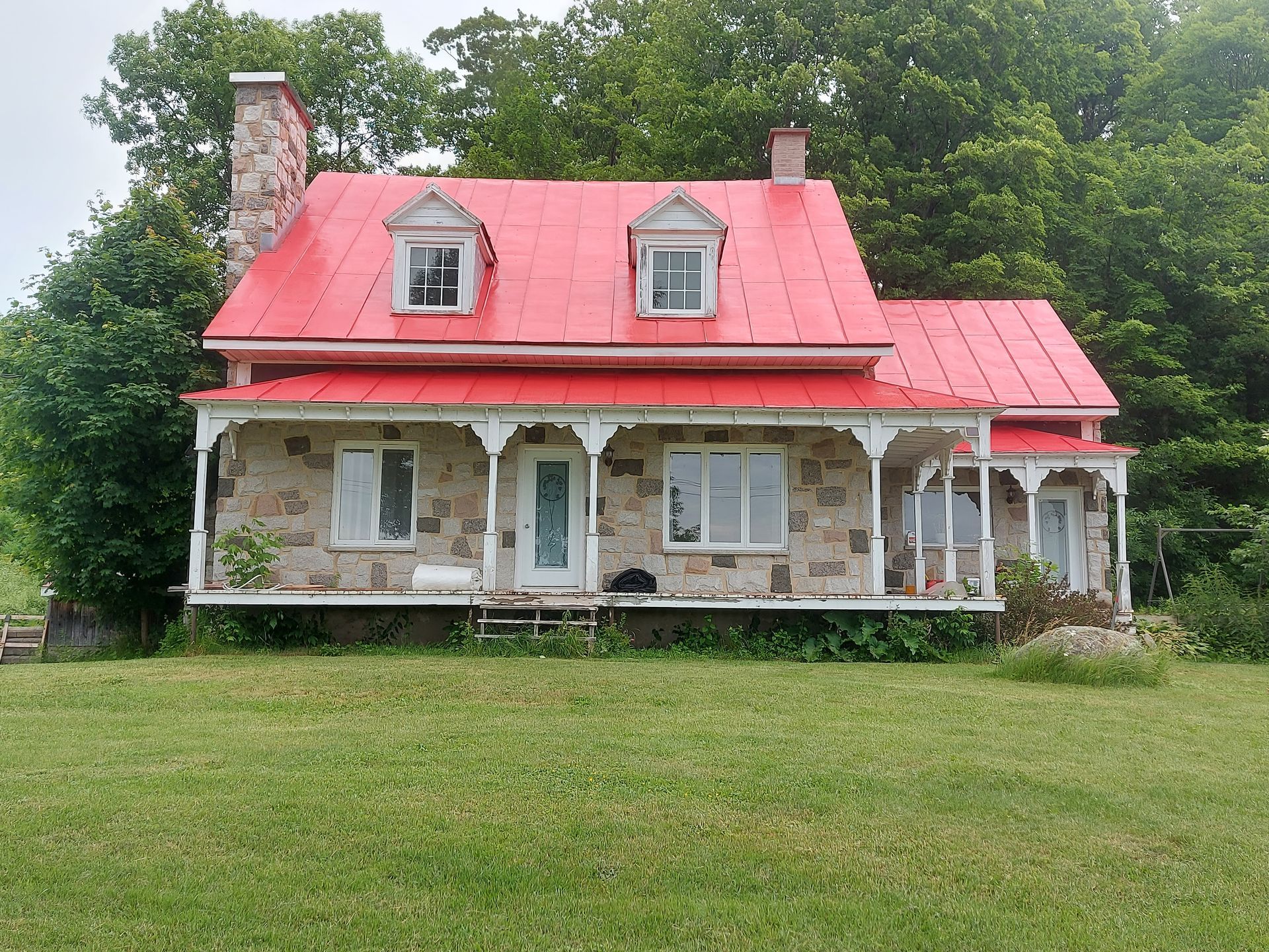 Une maison en pierre avec un toit rouge et un porche