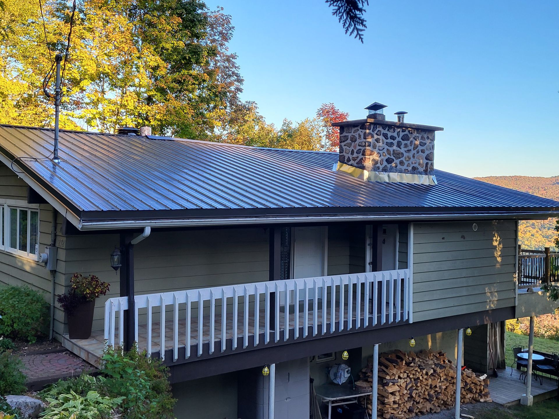 Une maison avec un toit en métal noir et un balcon.