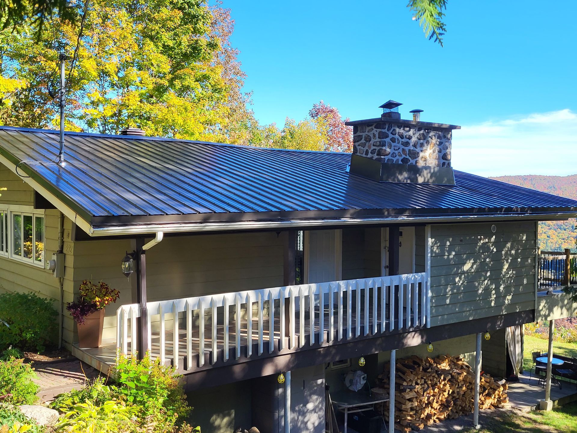 Une maison avec un toit noir et une terrasse blanche