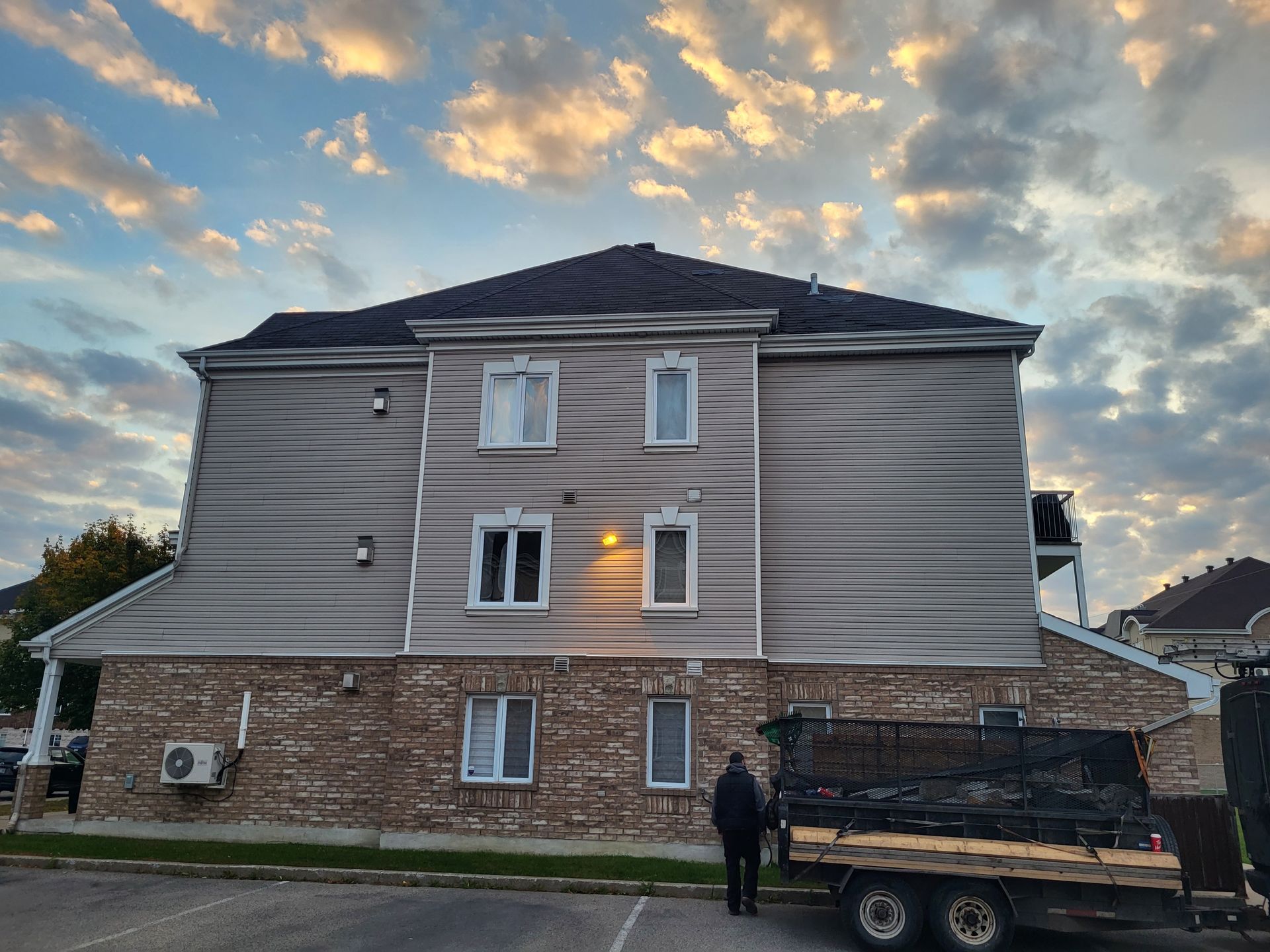 Un homme se tient devant un grand bâtiment avec un camion garé devant.