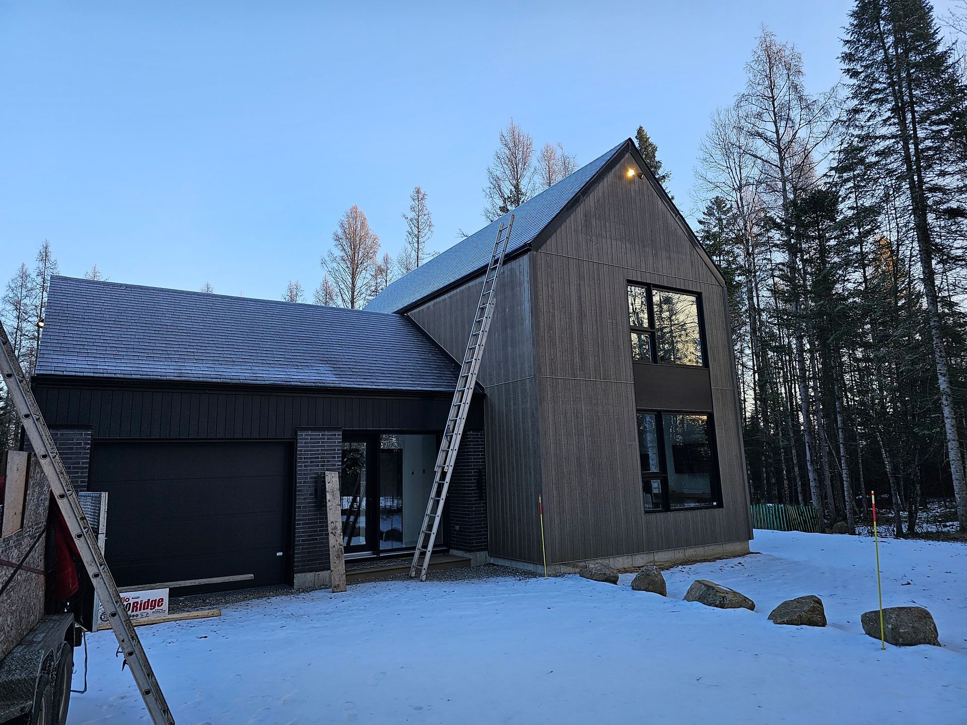 Une maison est en train d'être construite dans la neige avec une échelle devant elle.