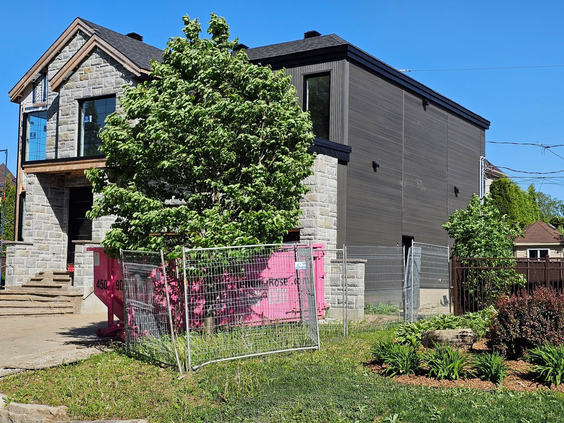 Une grande maison en briques avec une clôture rose devant.