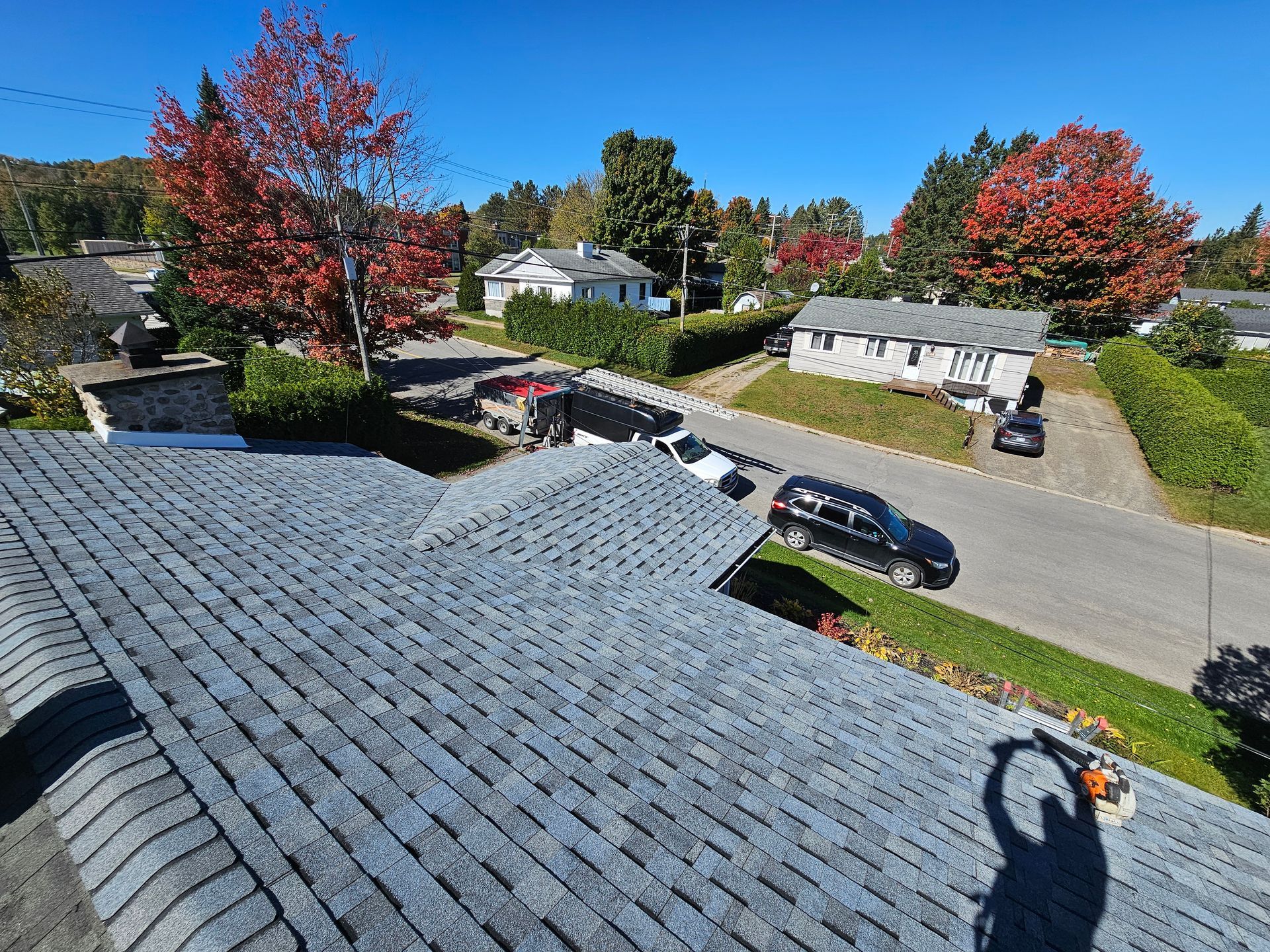 Un homme travaille sur le toit d'une maison dans un quartier résidentiel.