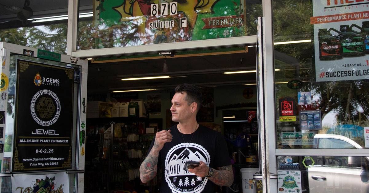 A man in a black shirt is standing in front of a store.