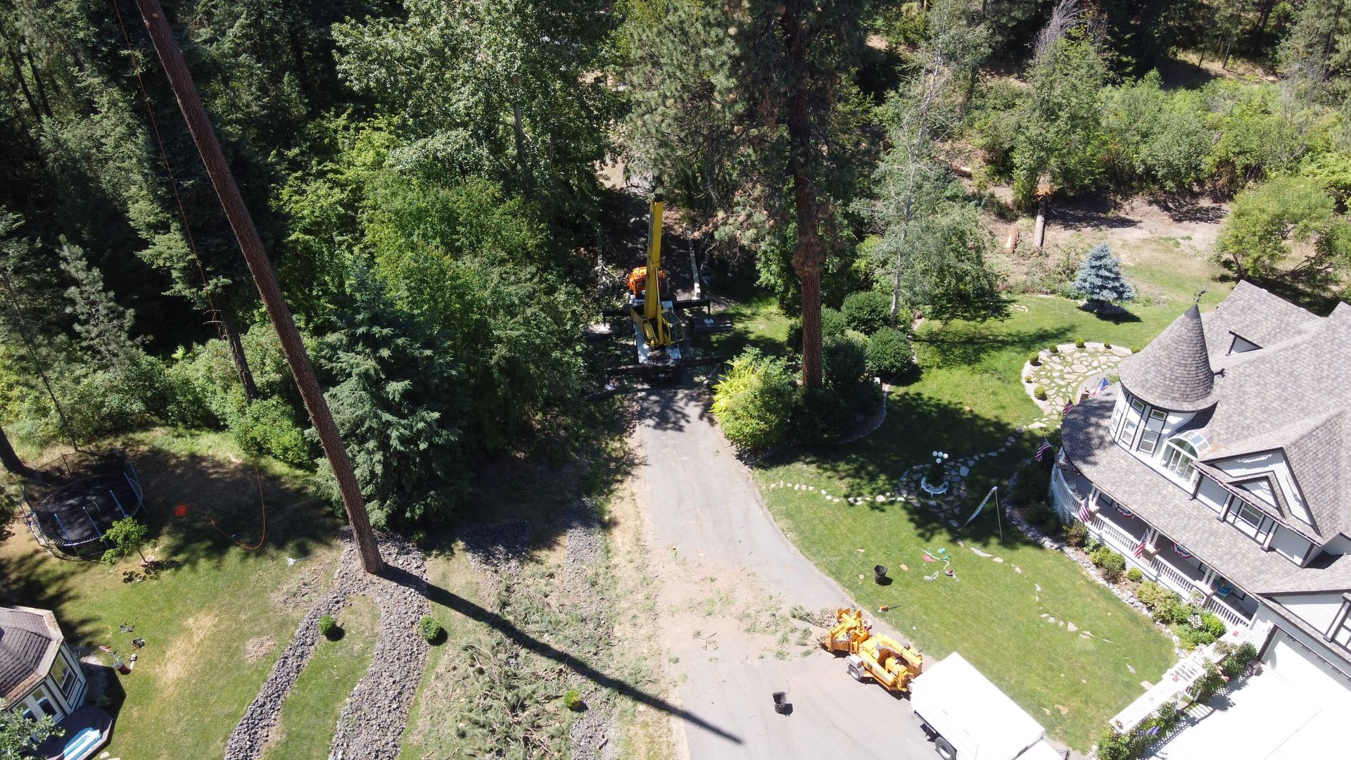 An aerial view of a tree being cut down in front of a house.