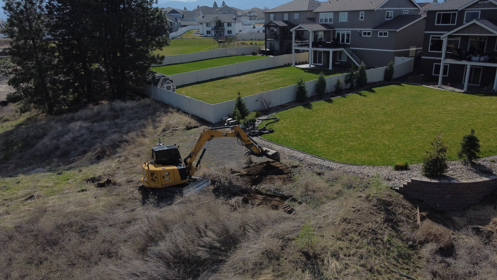 An aerial view of a bulldozer digging a hole in a yard.