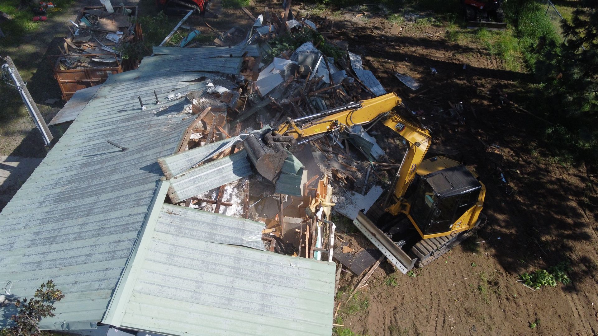 An aerial view of a house being demolished by a bulldozer.