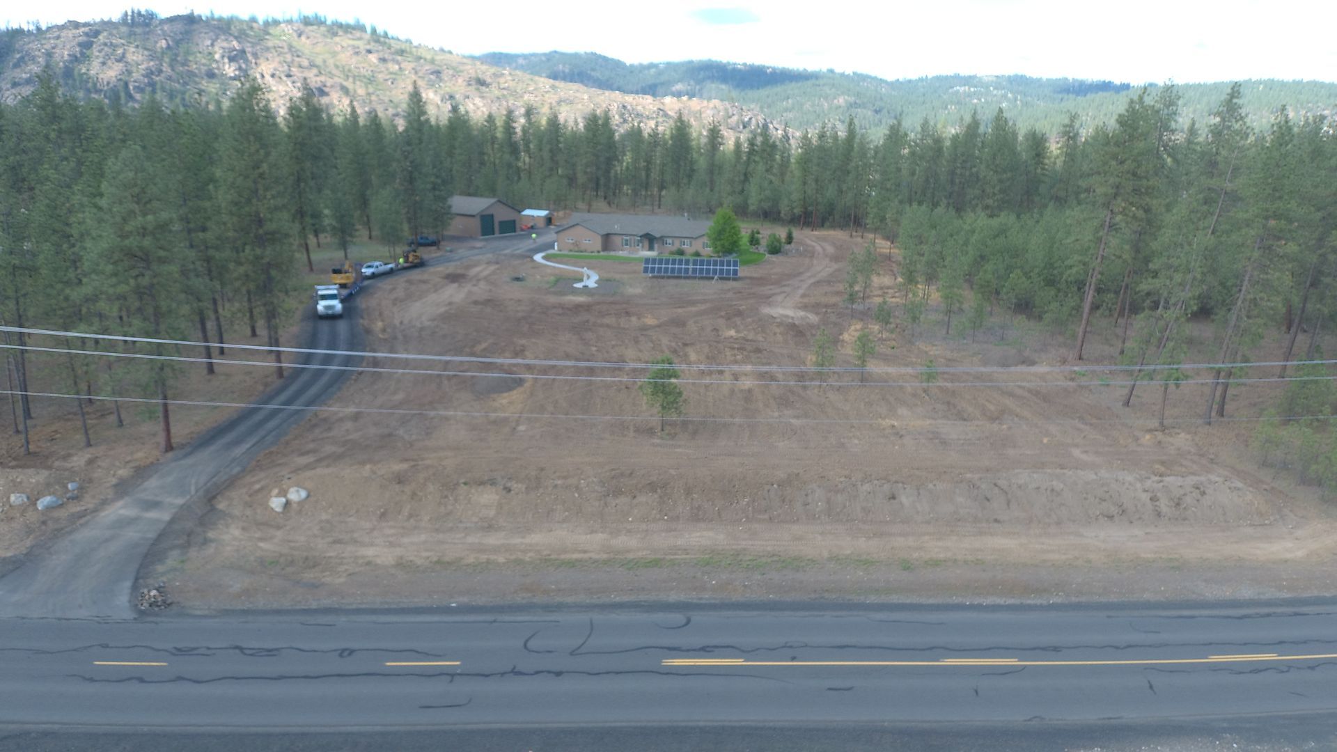 An aerial view of a road going through a lush green forest.