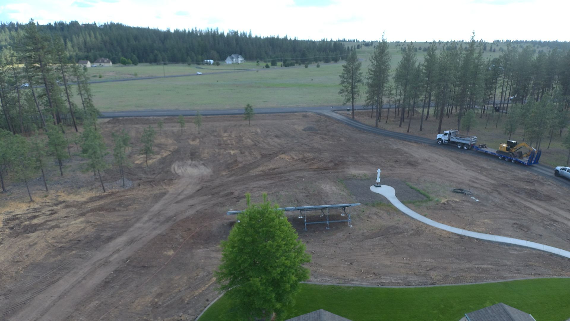 An aerial view of a construction site with a lot of dirt and trees in the background.