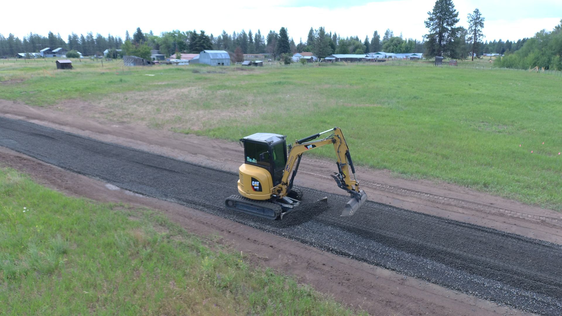 A small excavator is driving down a dirt road.
