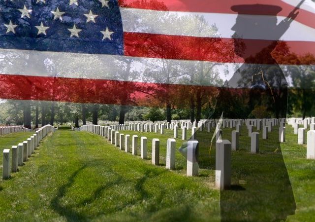 a soldier is standing in front of an american flag in a cemetery .