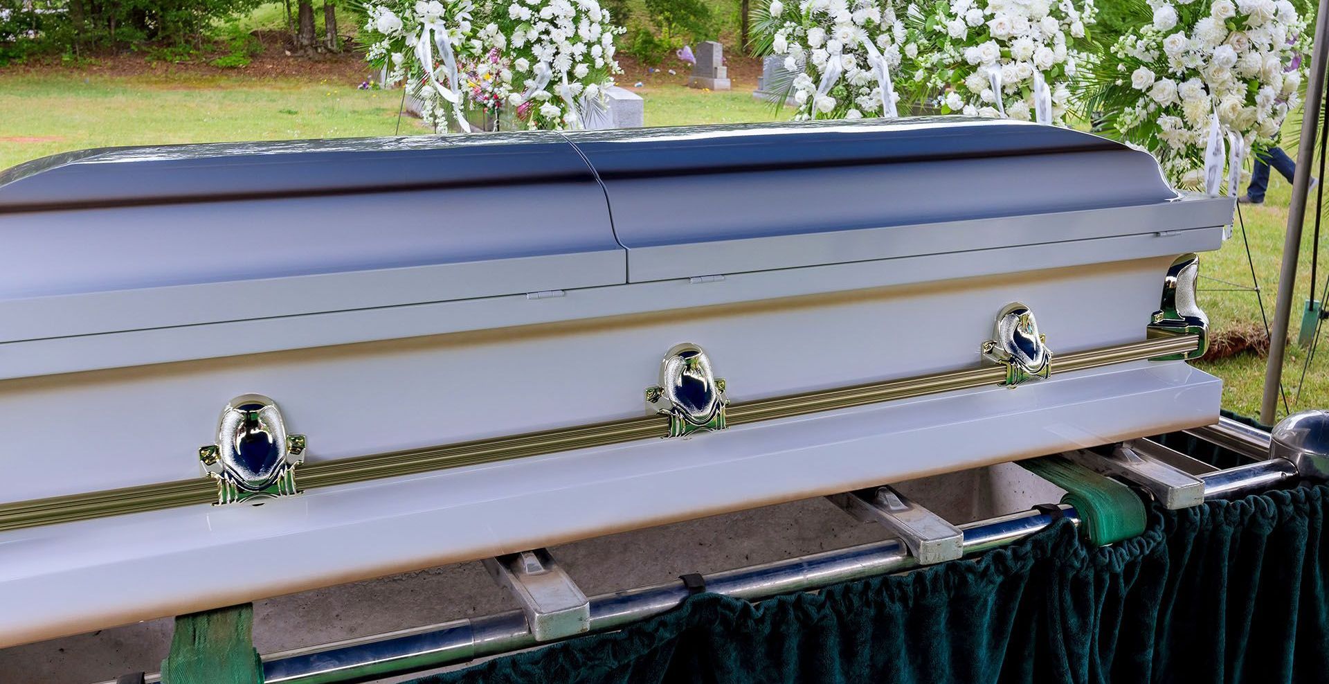 a white coffin is sitting under a tent in a cemetery .