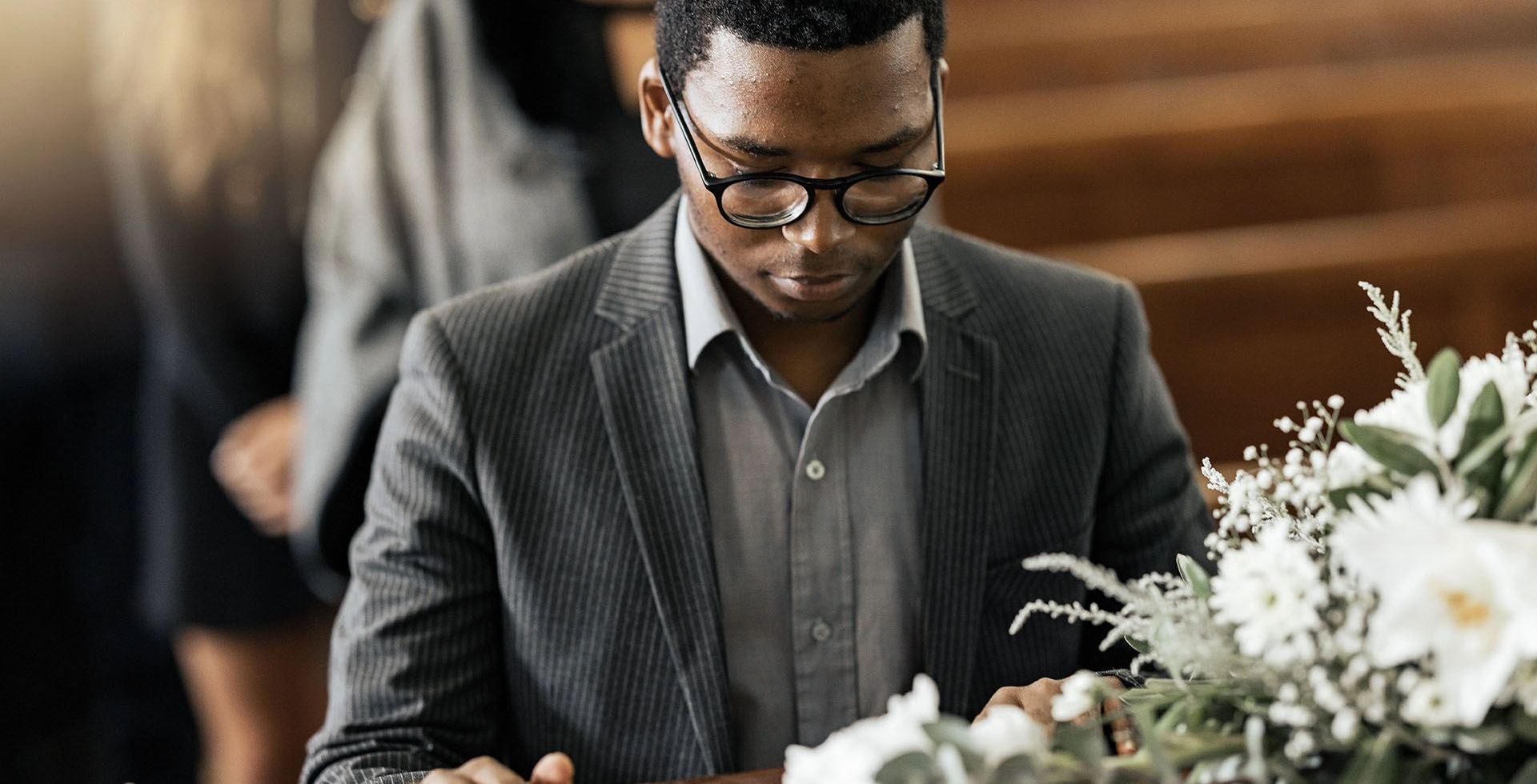 a man in a suit is sitting at a coffin at a funeral .