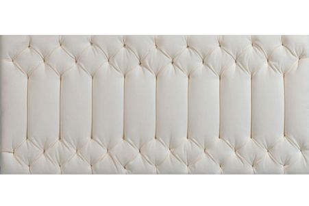 a close up of a white tufted headboard on a white background .