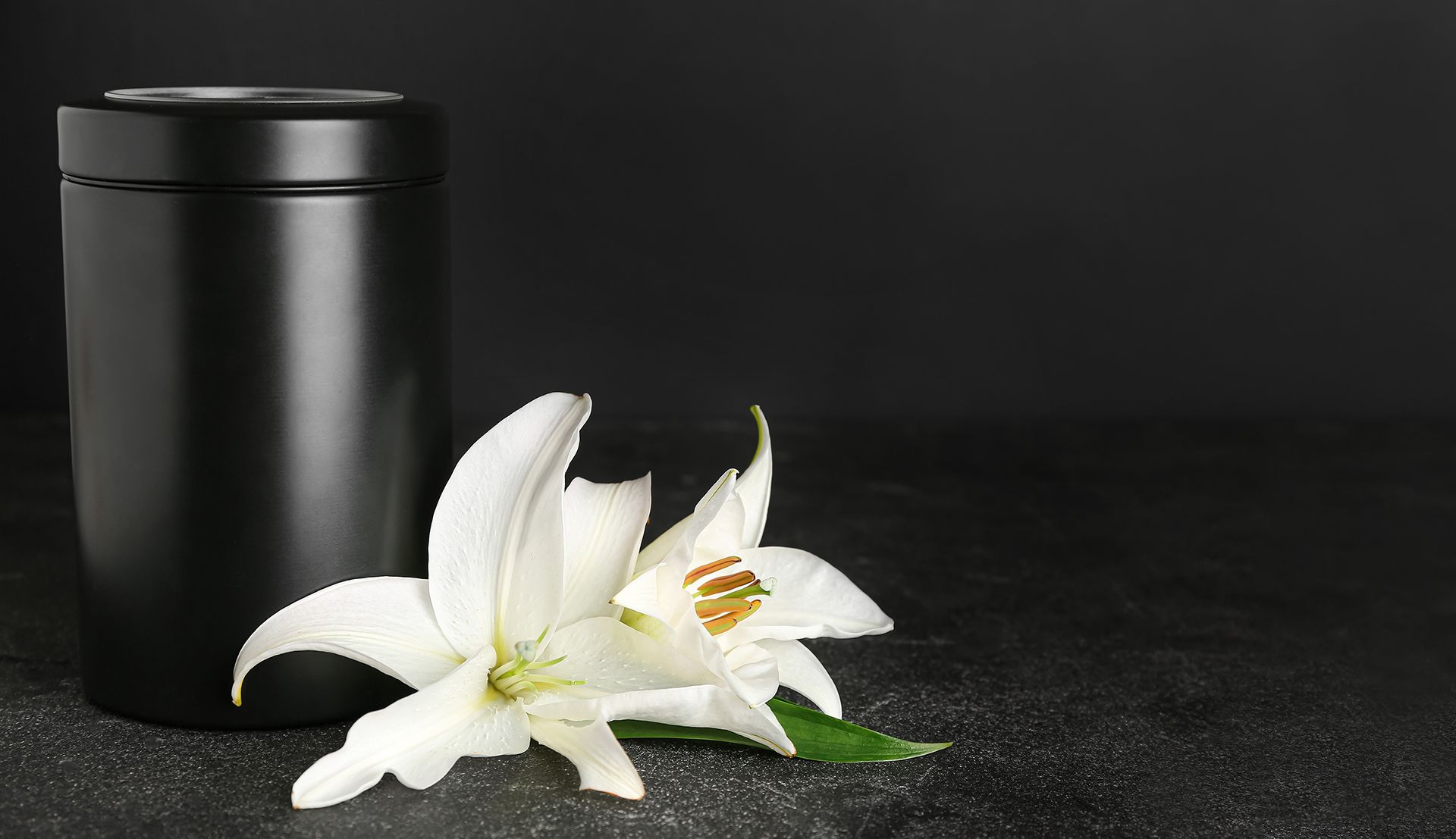 a black urn with a white lily on a black table .