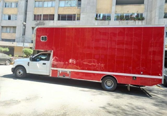 Un camión rojo y blanco está estacionado frente a un edificio.