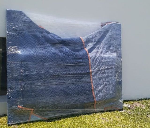 Un mueble grande está envuelto en plástico y sentado sobre el césped.