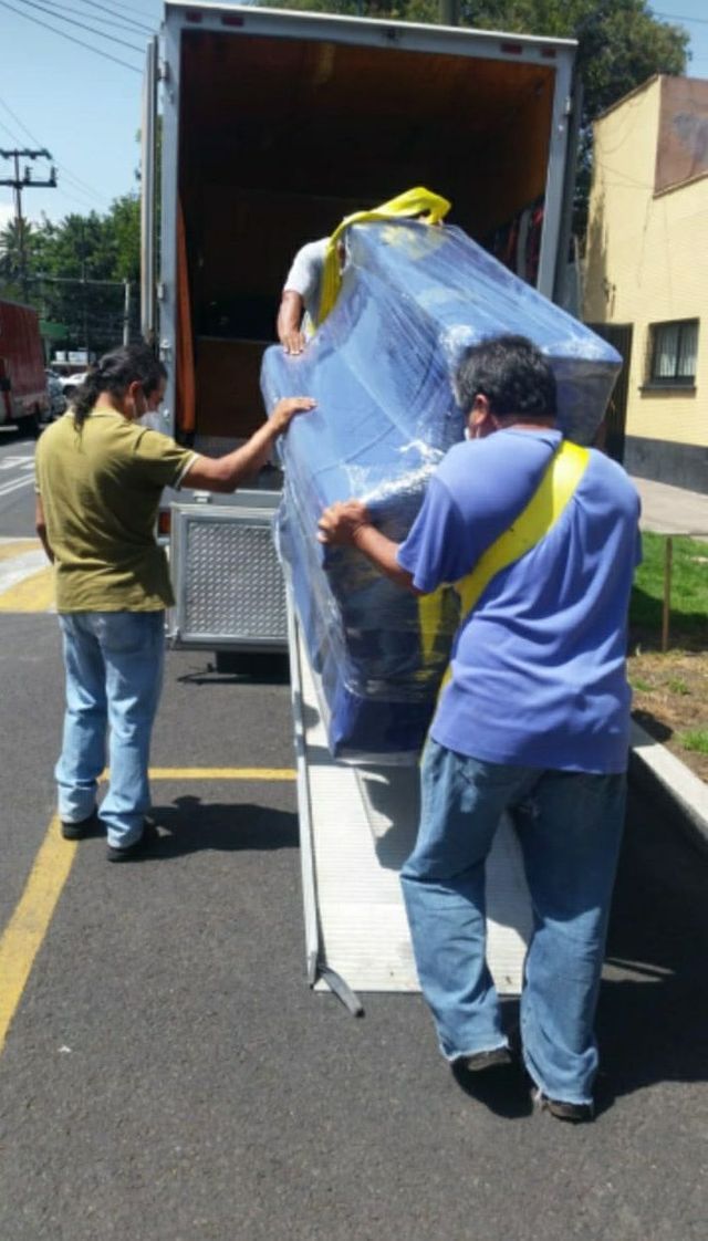 Un hombre con una camisa azul lleva un mueble grande