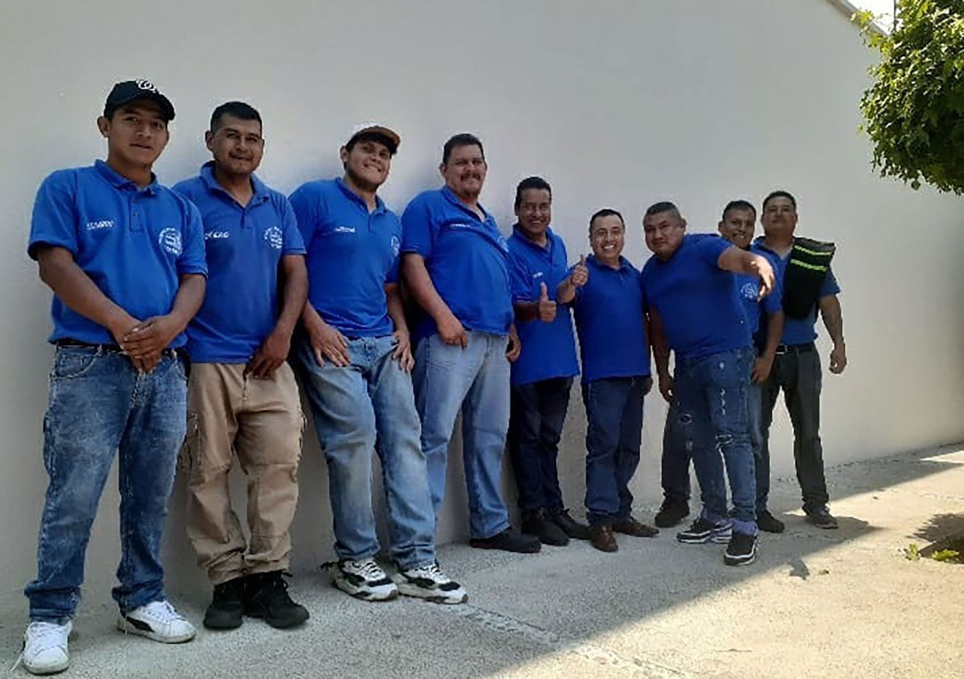Un grupo de hombres con camisas azules posan para una fotografía.