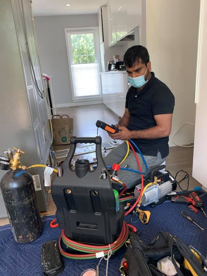 A man wearing a mask is sitting on the floor working on a machine.