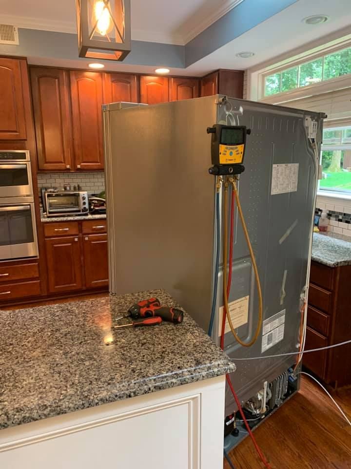 A refrigerator is being repaired in a kitchen.