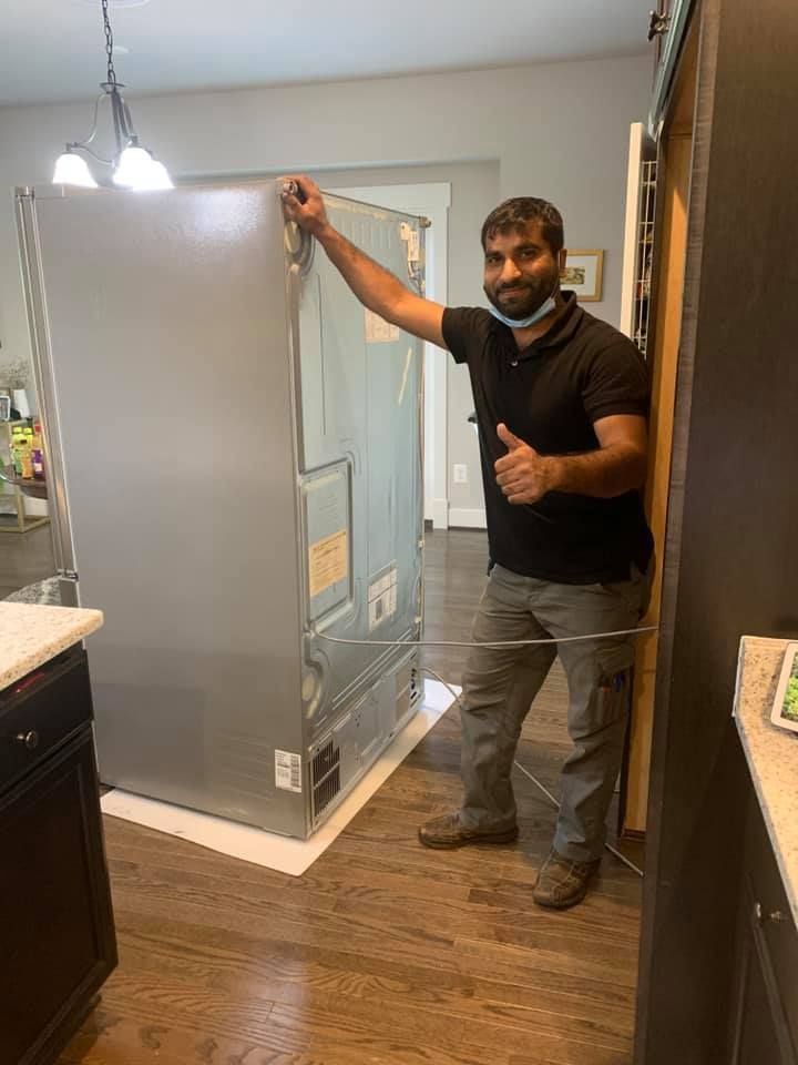 A man is standing next to a refrigerator in a kitchen.