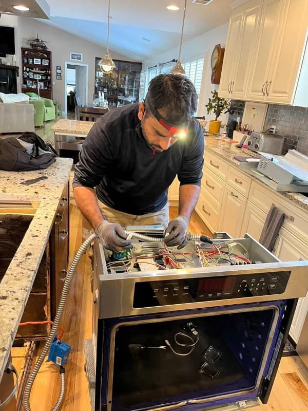 A man is working on an oven in a kitchen.