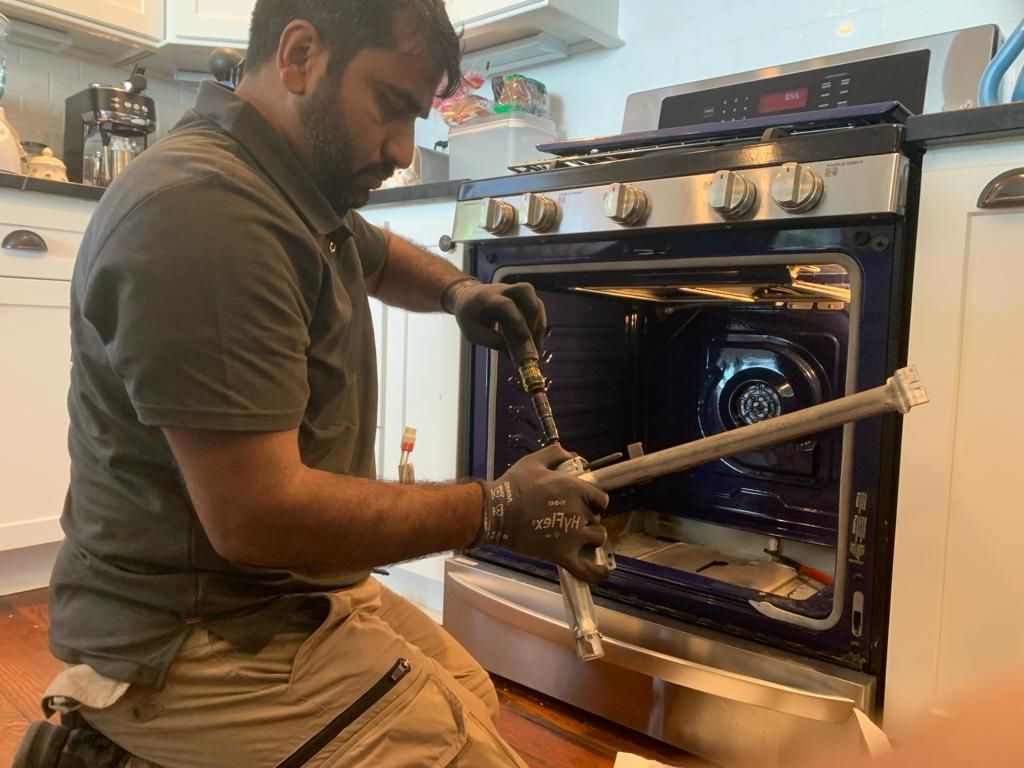 A man is working on a stove in a kitchen.