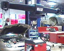 A car is on a lift in a garage with the hood open.