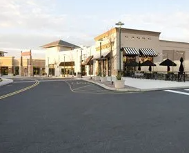 A shopping center with a lot of shops and umbrellas on the side of the road.
