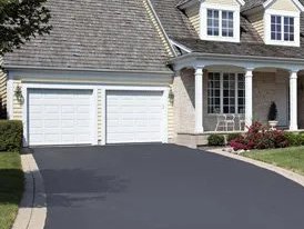 A house with two garage doors and a driveway leading to it.