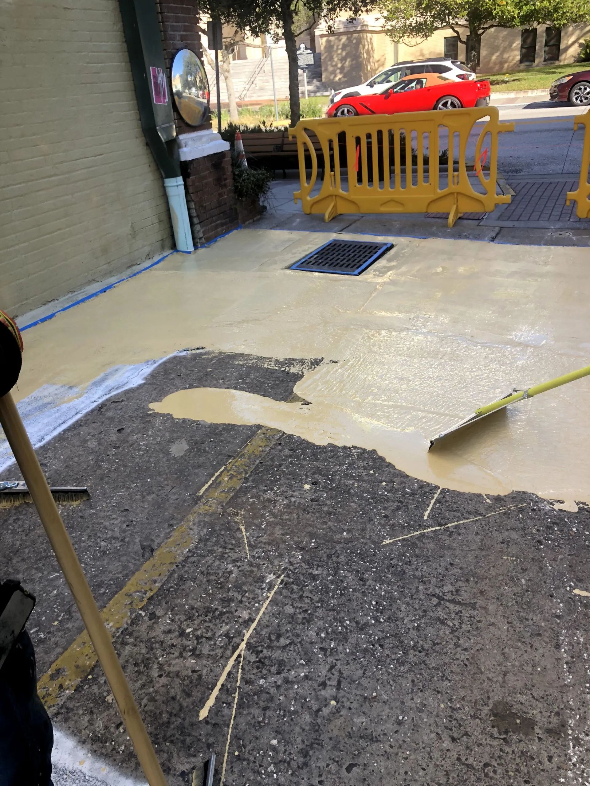 A person is cleaning a sidewalk with a broom.