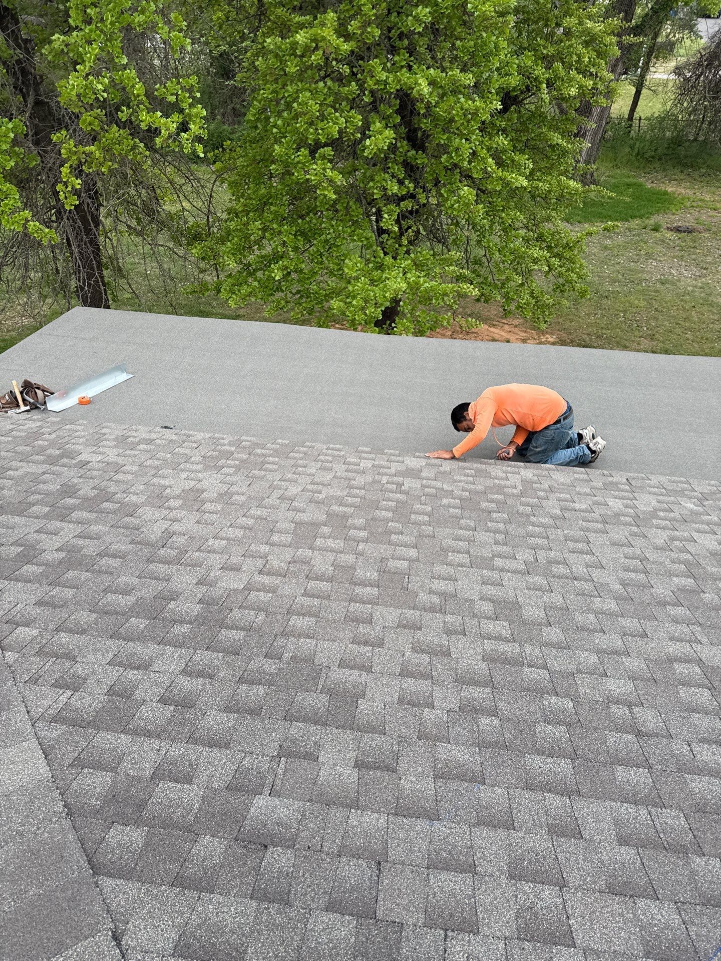 A man is kneeling on top of a roof.