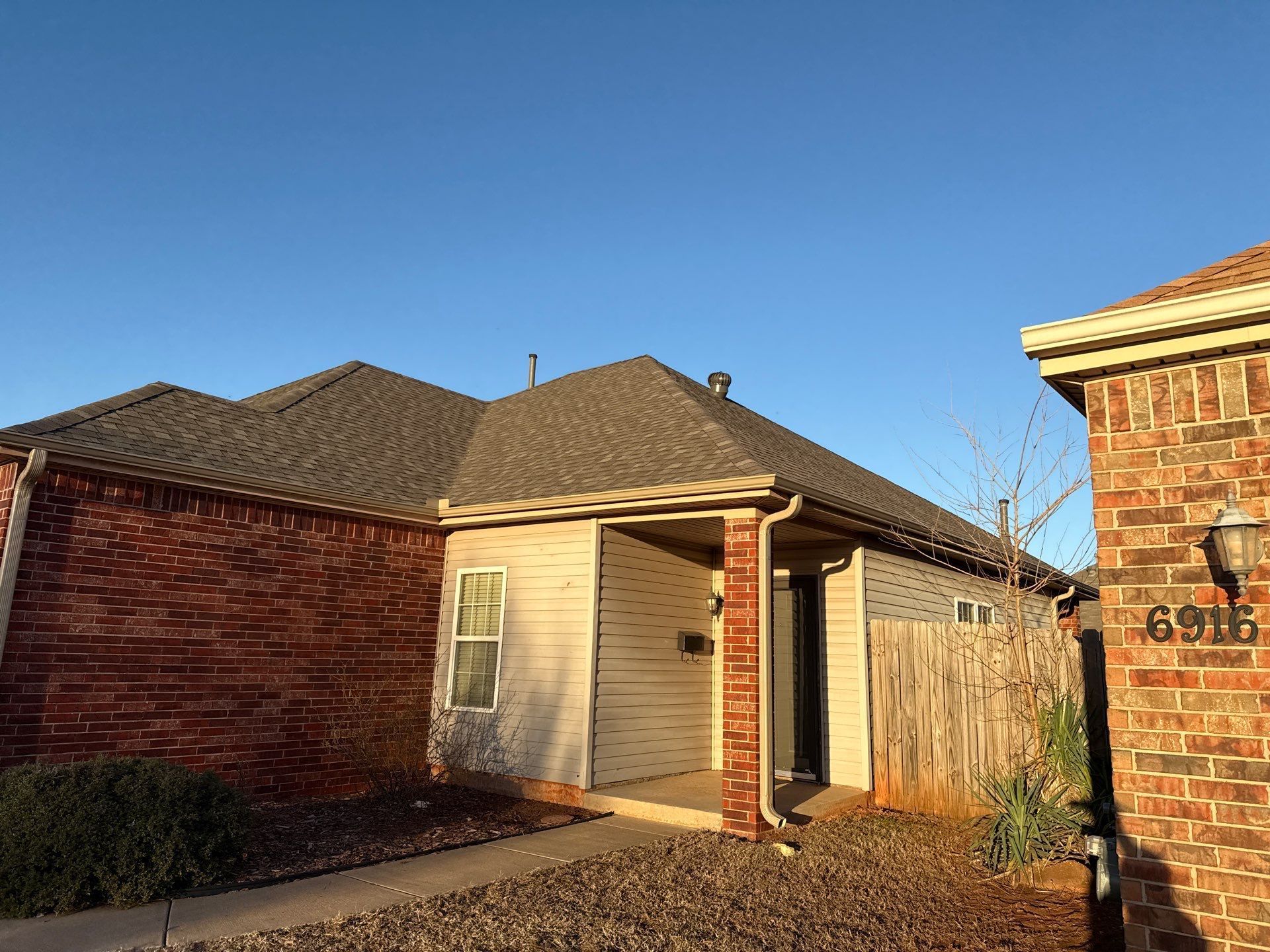 A brick house with a roof that is covered in shingles