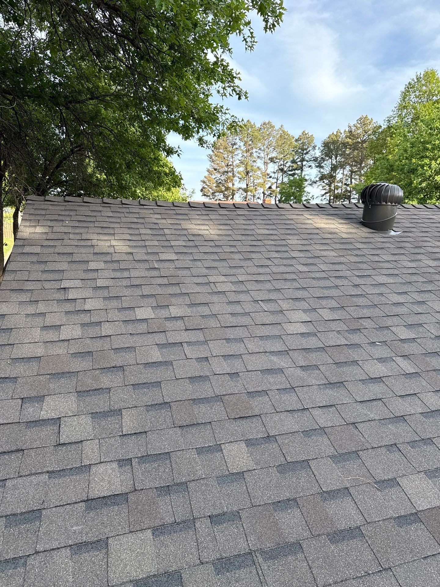 A roof with a chimney on it and trees in the background.