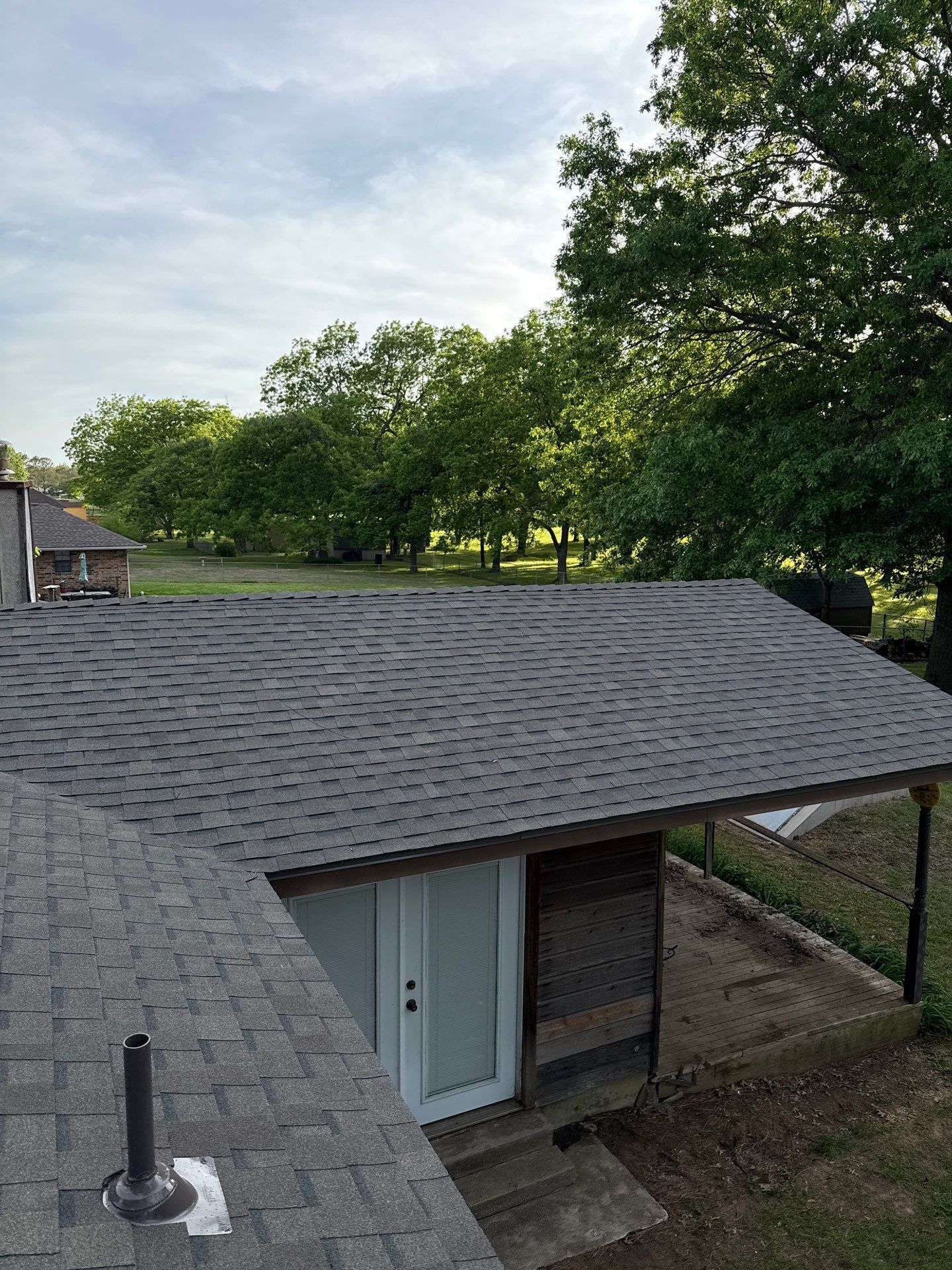 A roof of a house with a door and trees in the background.