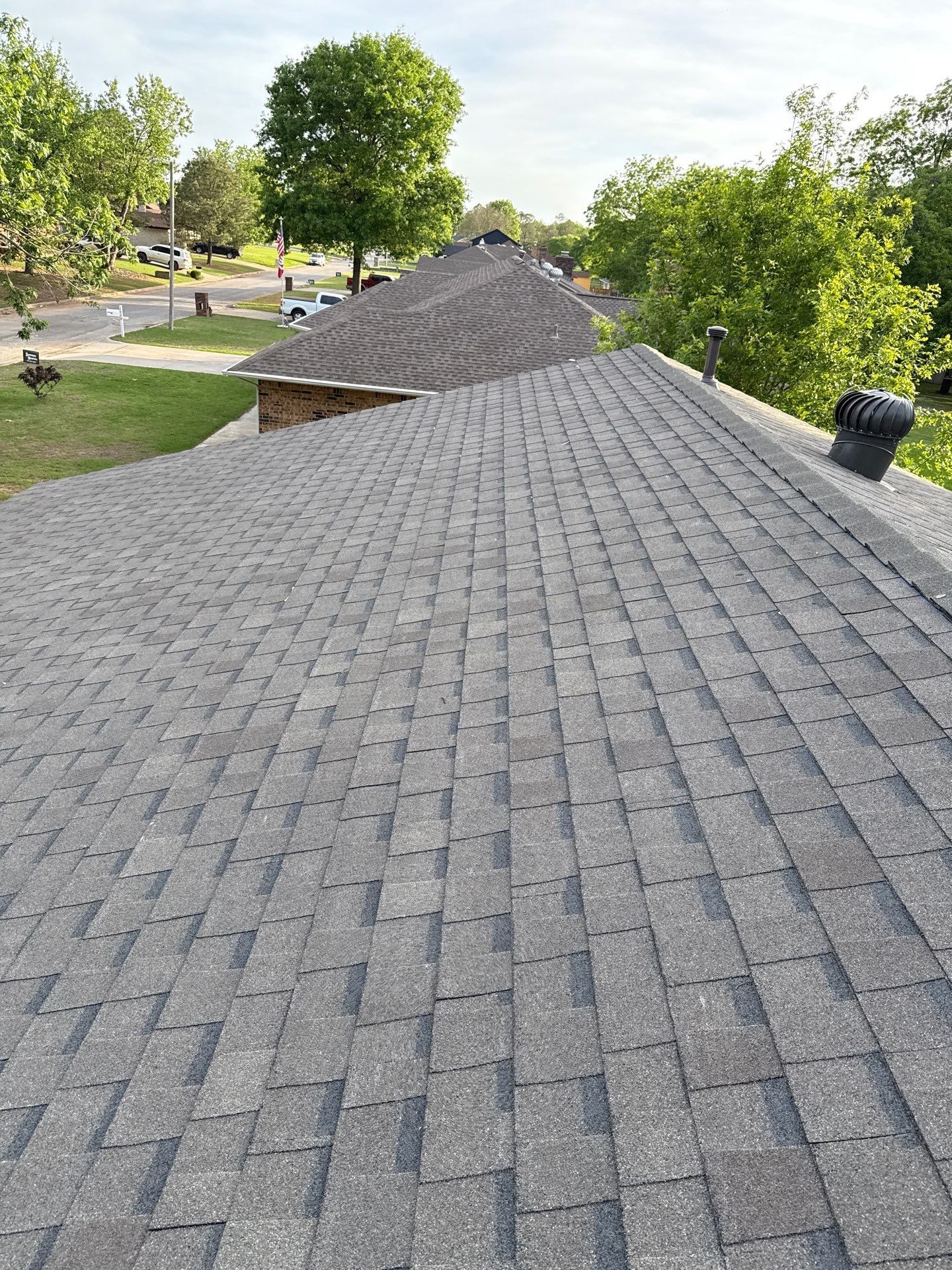 A roof with a lot of shingles on it and trees in the background.