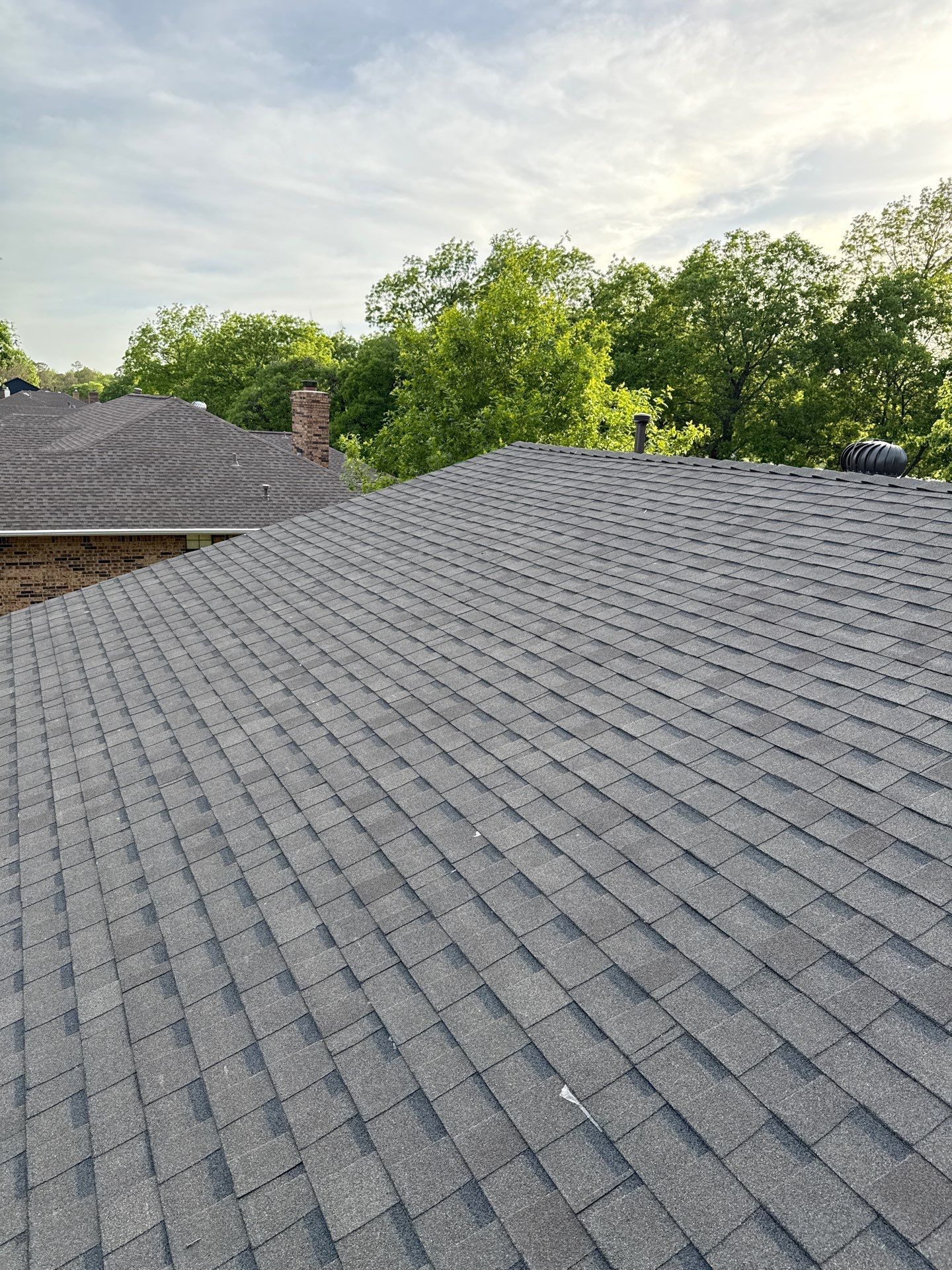 A close up of a roof with a chimney and trees in the background.
