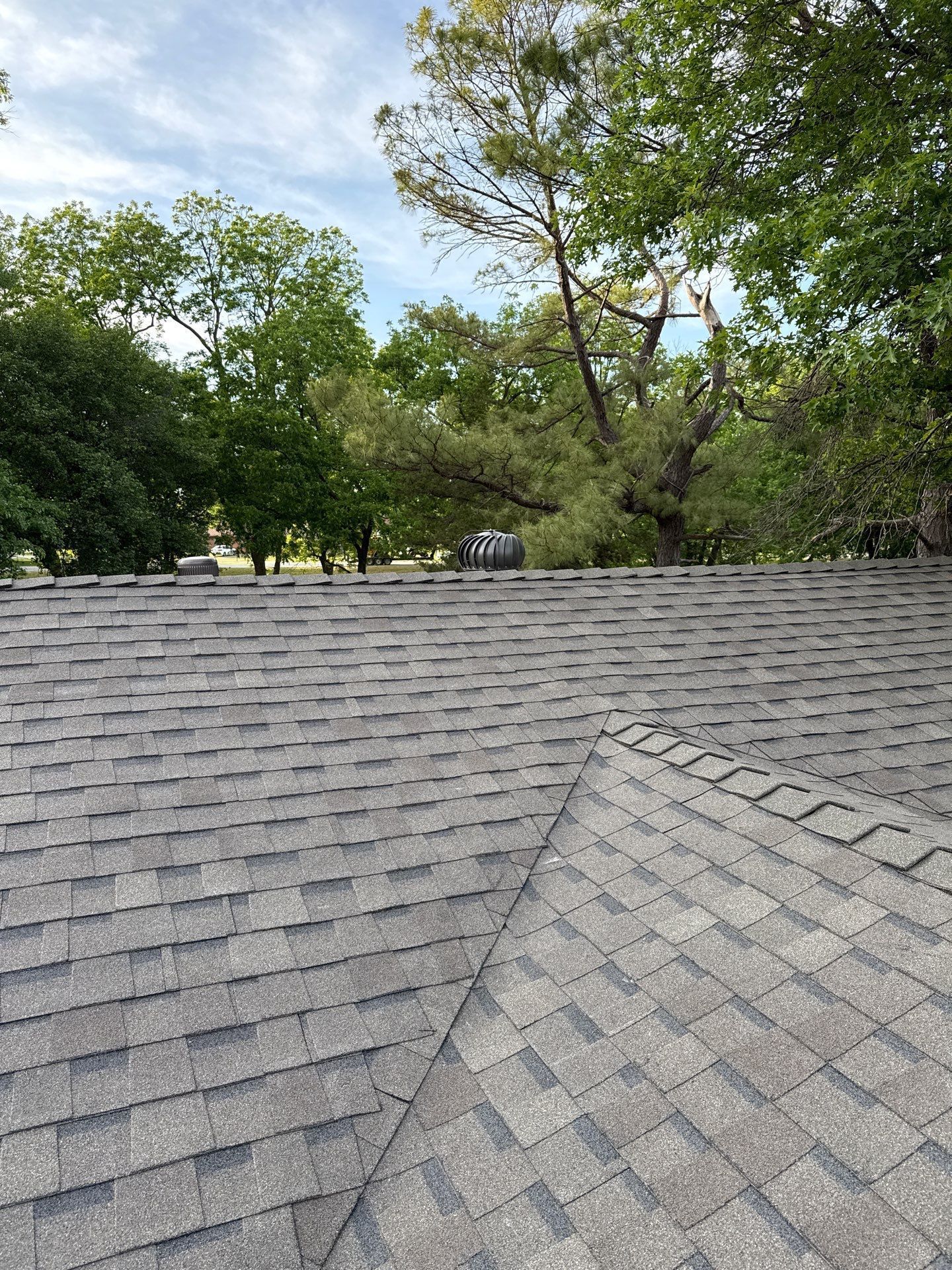 A roof with a lot of shingles and trees in the background.