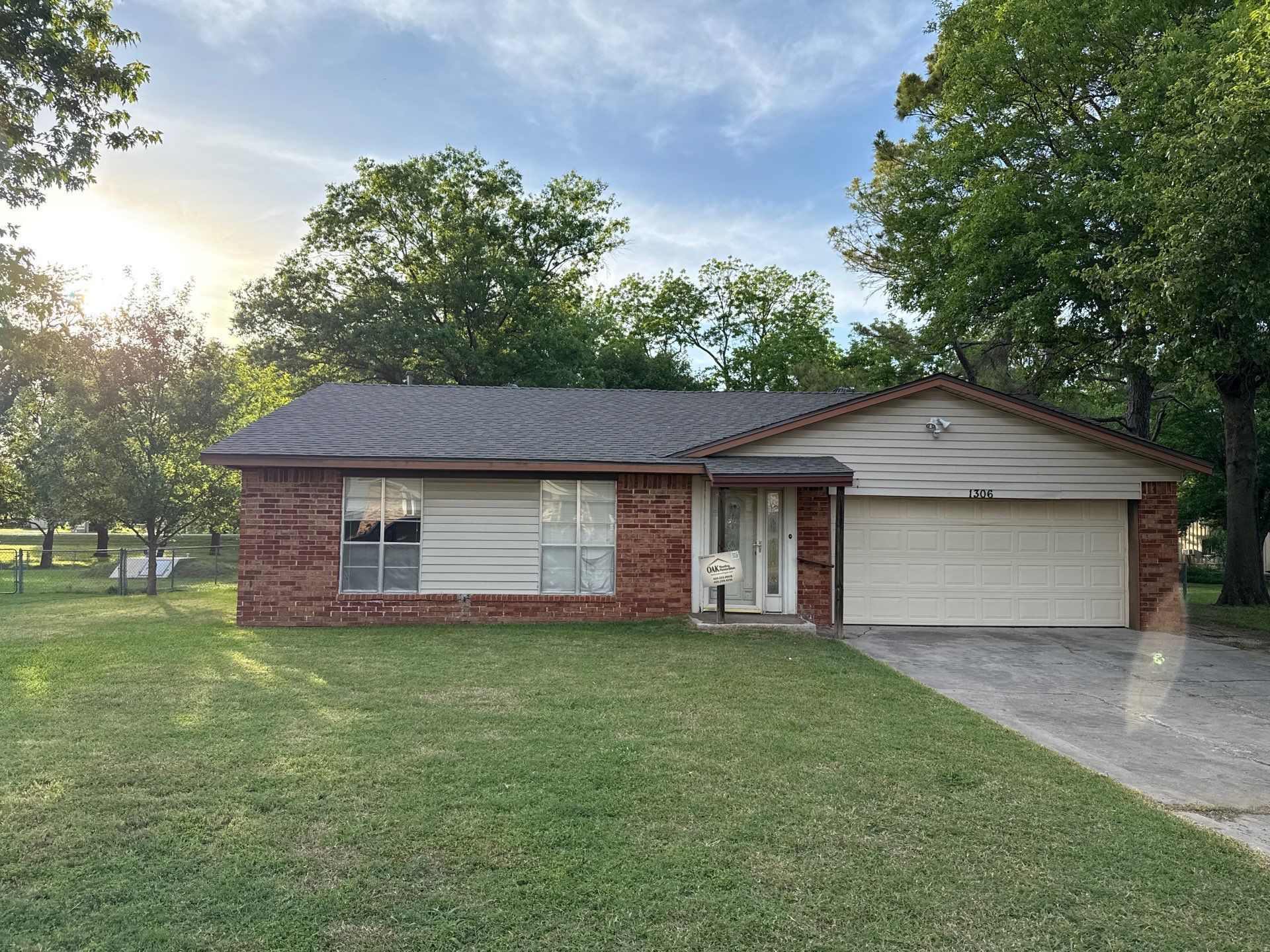 A brick house with a white garage door and a large lawn in front of it.