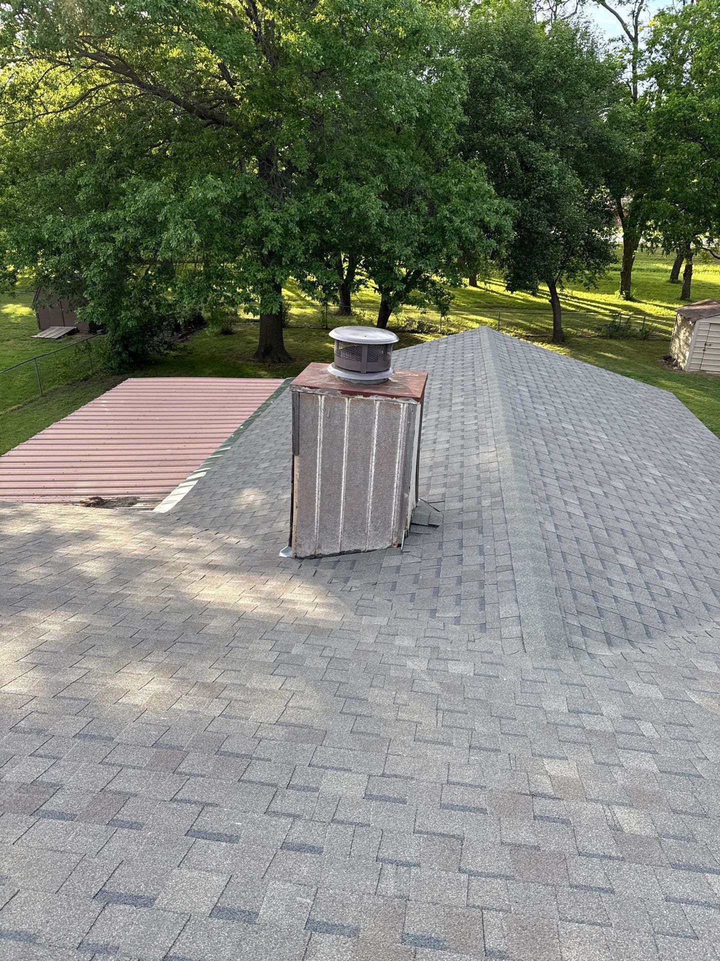 A roof with a chimney on top of it and trees in the background.