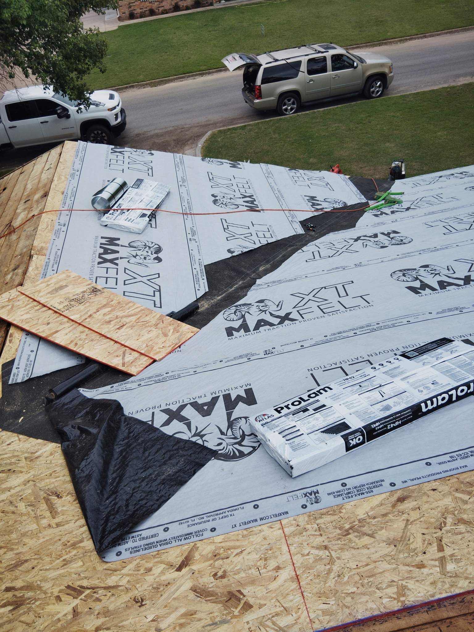 An aerial view of a roof under construction with a truck parked in the background.