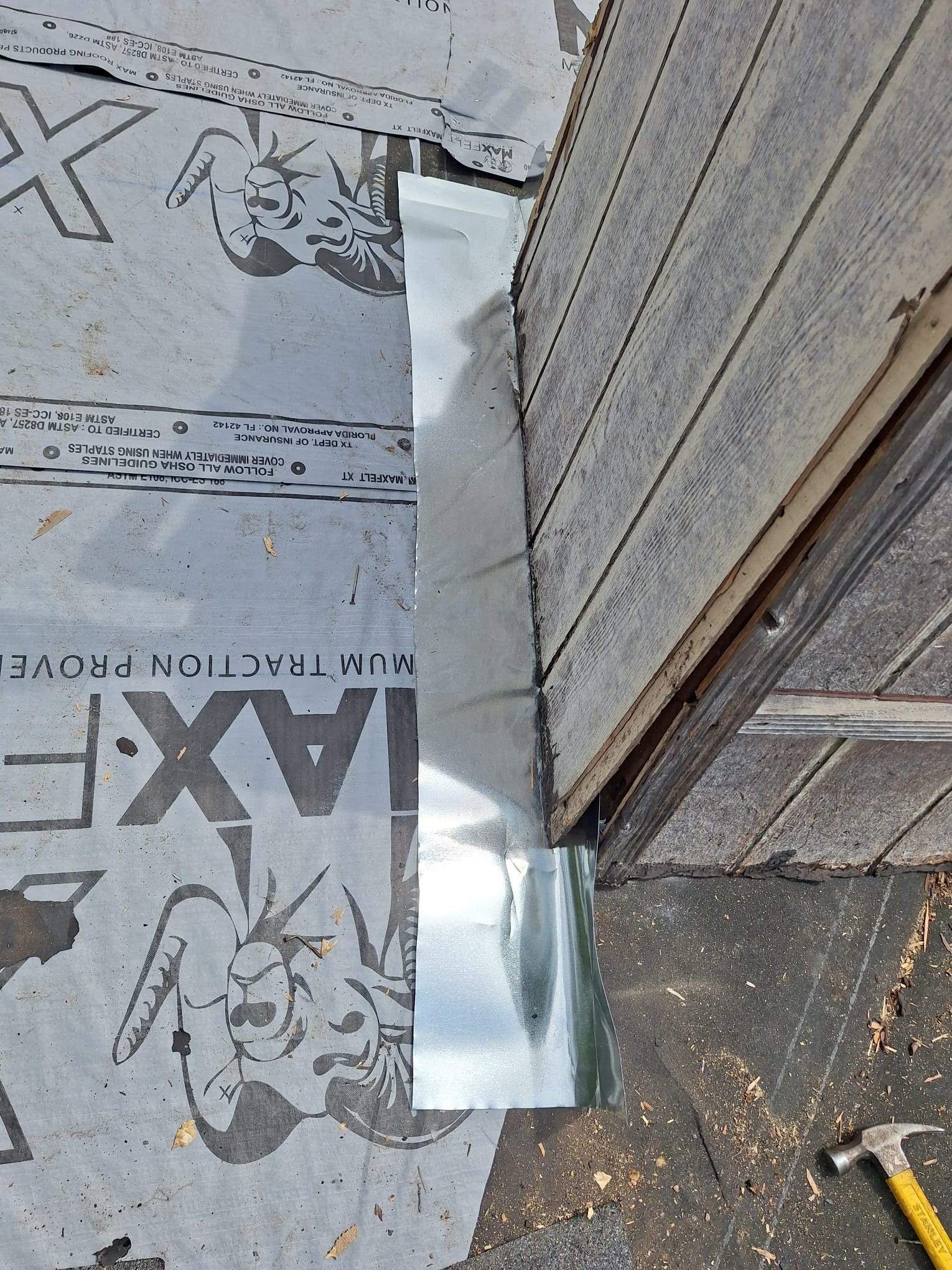 A piece of metal is sitting on the ground next to a hammer.